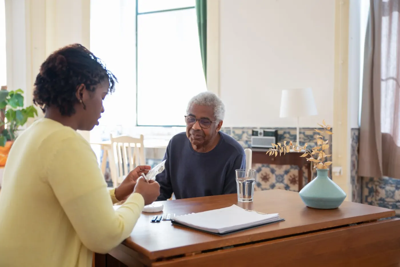 A caregiver sitting with a resident at a table, reviewing papers together